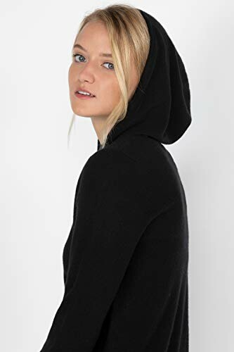 Woman wearing a black hoodie, looking over her shoulder